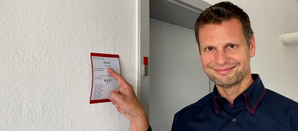 Mann zeigt lächelnd auf ein Schild