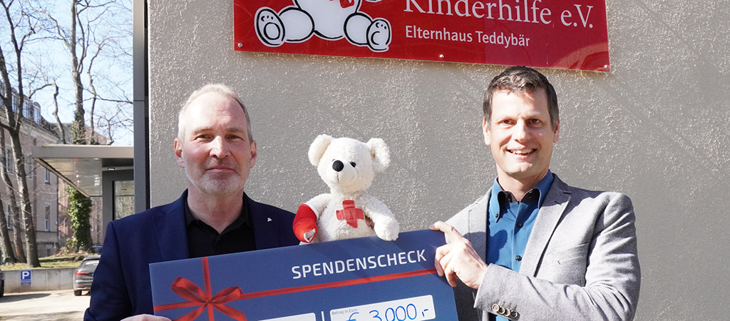 Zwei Personen halten einen Spendenscheck in der Hand und lächeln