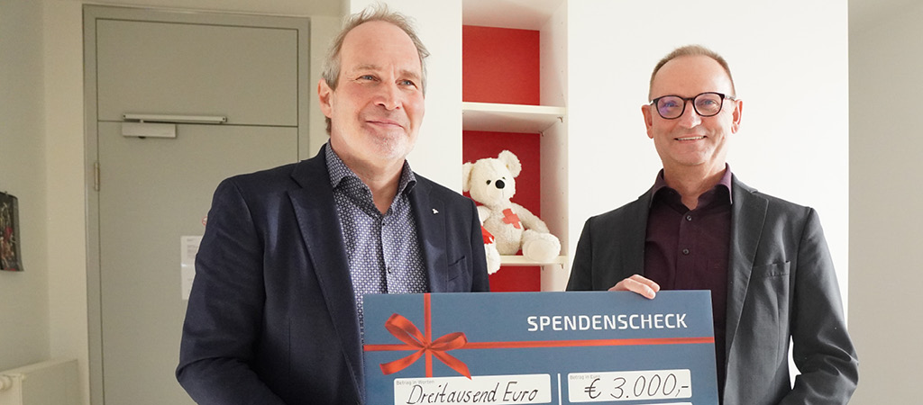 Zwei Personen mit Spendenscheck und Teddybär
