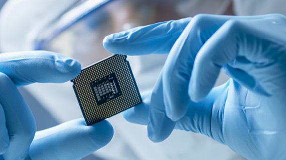 Operator mit blauen Handschuhen hält einen Chip in der Hand