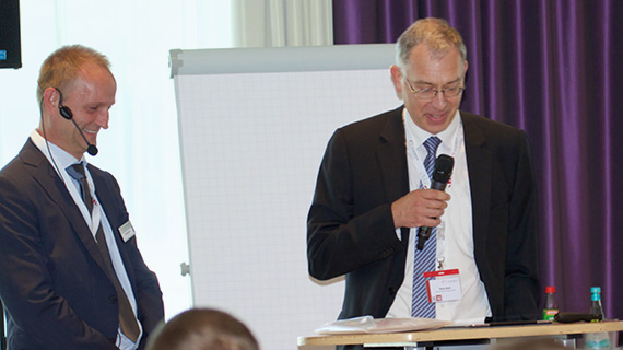 Zwei Personen in Anzügen mit Mikrofonen