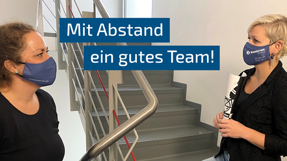 Zwei Personen mit Mundnasenschutz in einem Treppenhaus