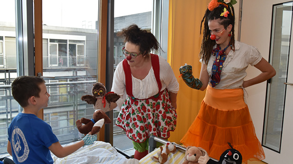 Zwei Clowns und ein Kind in einem Krankenhauszimmer