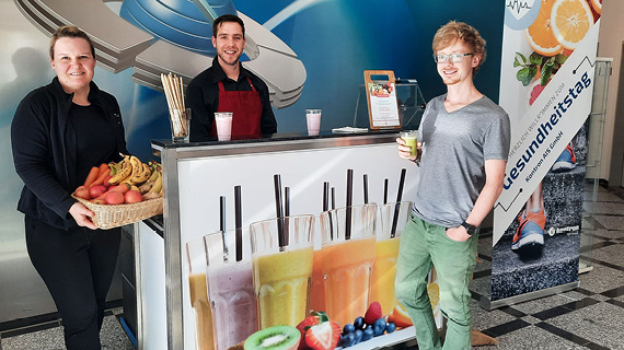 Drei Personen stehen an einer Safttheke 