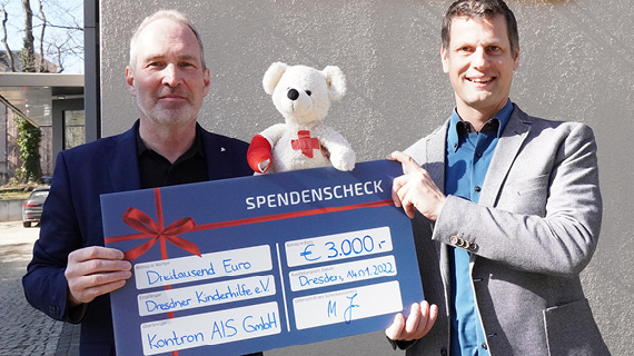 Zwei Personen halten einen Scheck in der Hand und einen Teddy