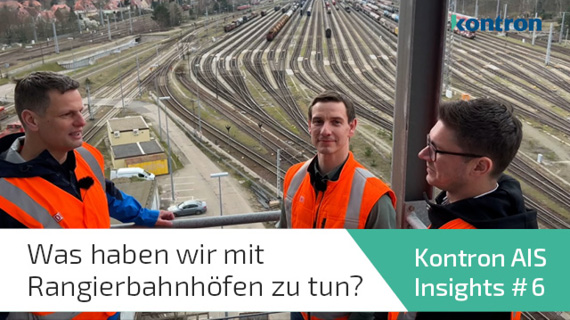 Drei Personen mit Bahngleisen im Hintergrund